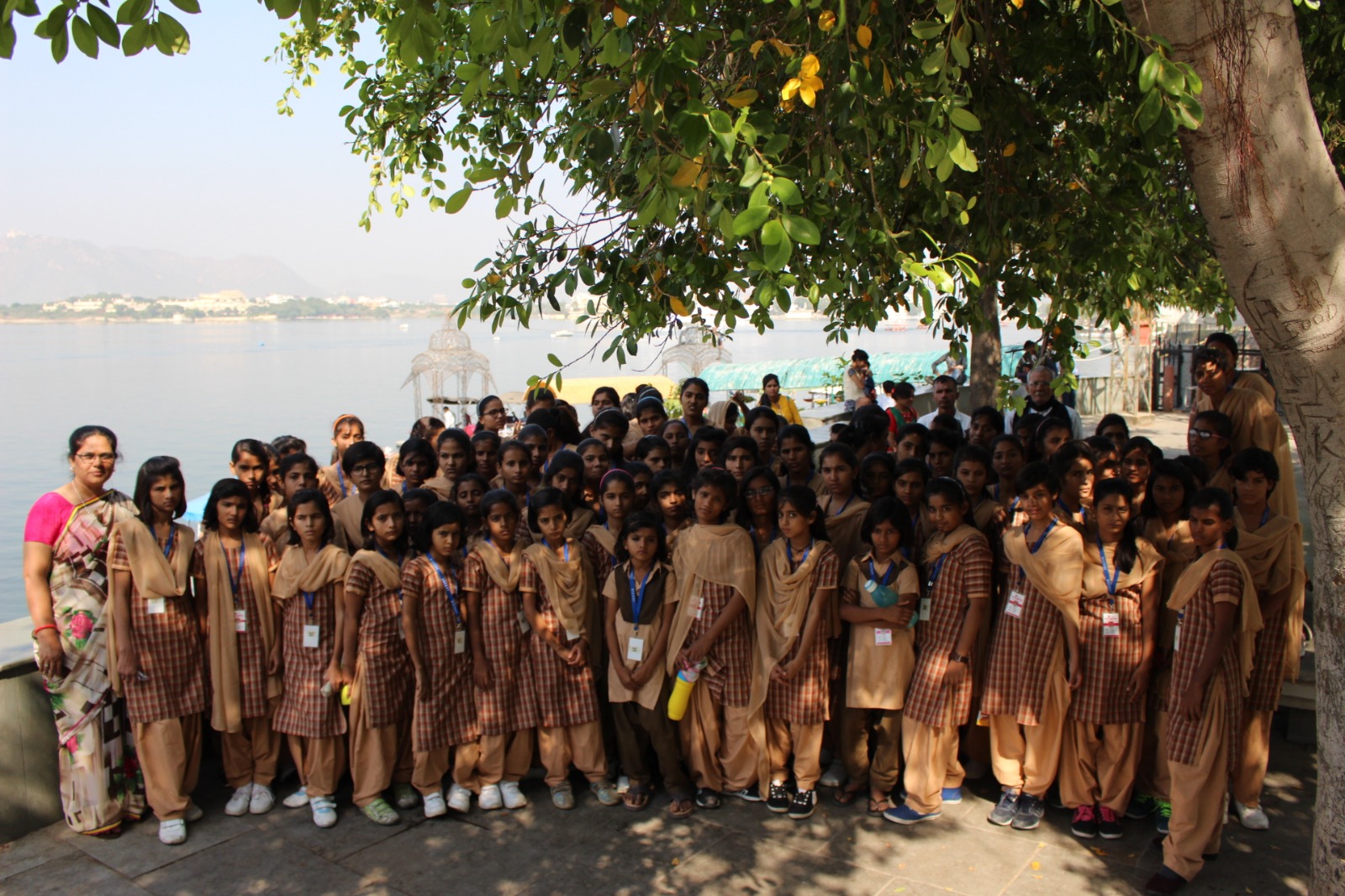 Students and teachers gathered under a tree during a visit