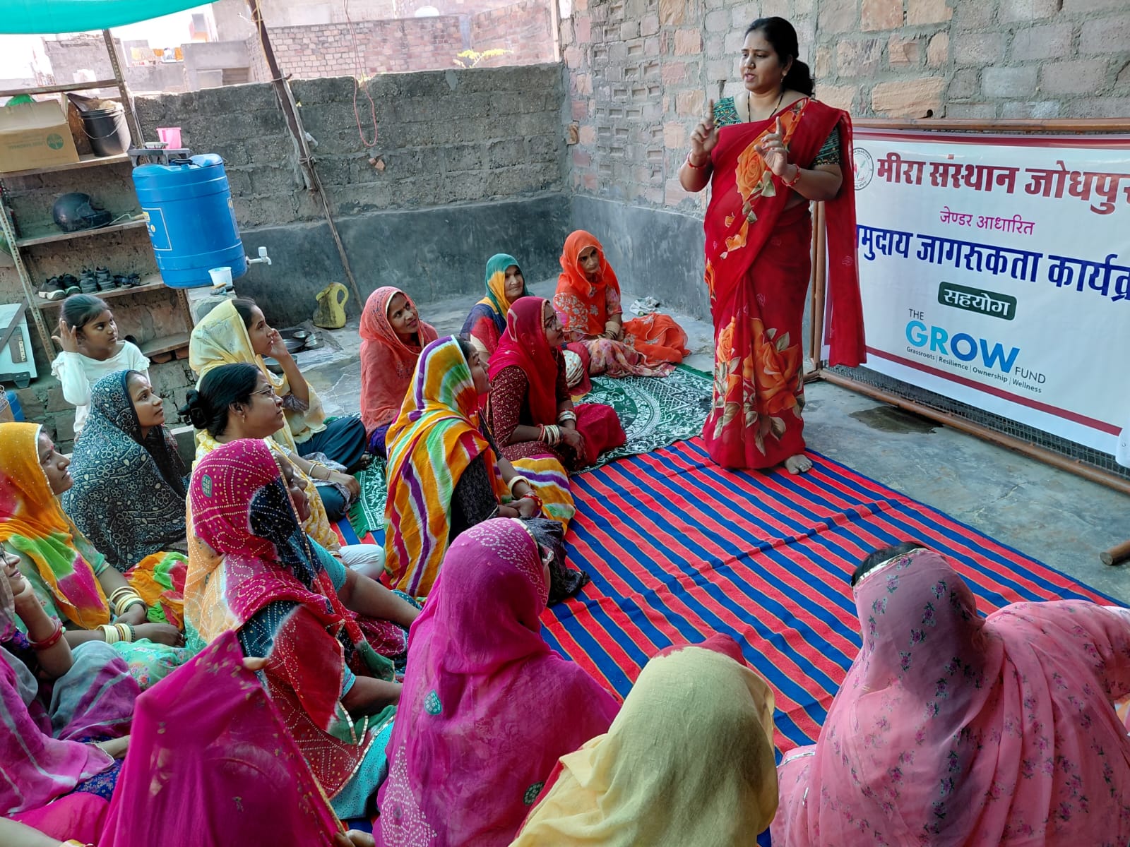A field worker speaking with women beside the GROW banner