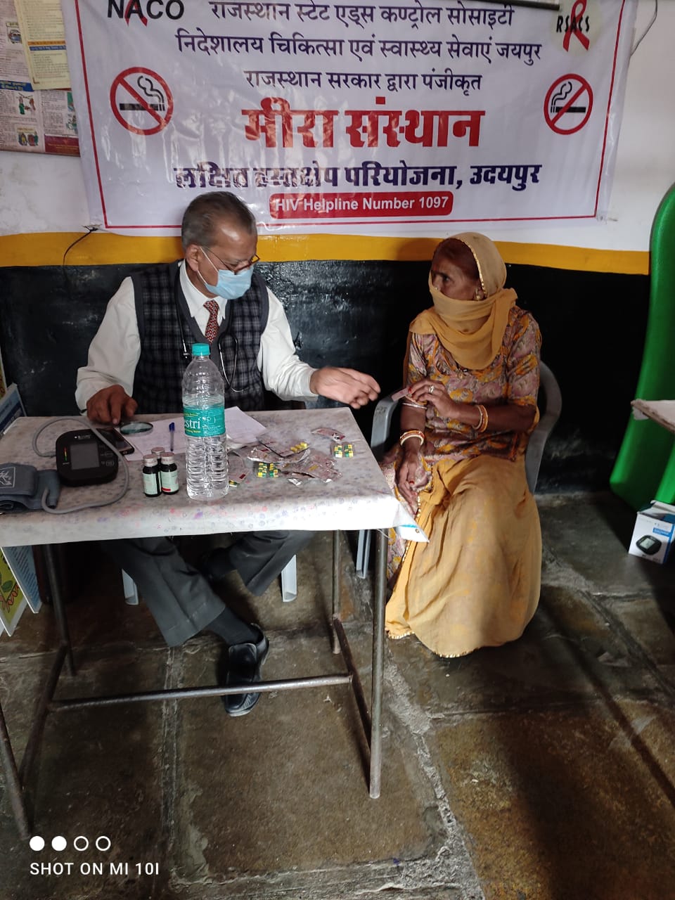 Two people seated by a health information banner